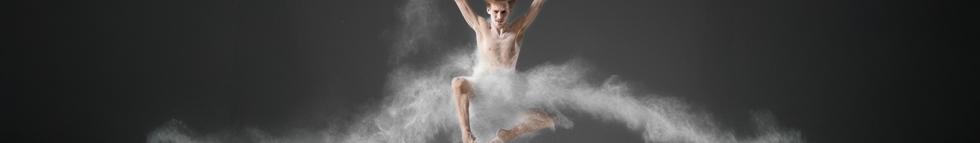 Ausschnitt des Fotos : Moderner Tänzer springt kraftvoll auf einer professionellen Tanzfläche, Staub hebt Dynamik und Bodenhaftung hervor als Stimmungsbild verwendet